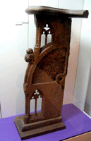 Diese mit zwei kleinen Maßwerkfenstern kunstvoll durchbrochen gearbeitete Wange gehörte zu einem hölzernen Chorgestühl, das wie zu dieser Zeit üblich, über hochklappbare Sitzflächen verfügte. Seit der Mitte des 13. Jahrhunderts gehört das Chorgestühl zur Grundausstattung jeder Kirche.Es ist bis heute unklar, aus welcher Kirche das ausgestellte Fragment eines Chorgestühls stammt.