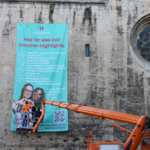 Stefan Gebauer und Eric Toth, Mitarbeiter des Halberstädter Stadt- und Landschaftspflegebetriebs installieren das Banner an der Fassade der Martinikirche.