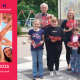 Die Ströbecker Grundschüler durften als Erste den Sommerferienkalender durchstöbern. - Ortsbür-germeister Jens Müller sowie Stefanie Schrader und Schulleiter  Volker Heinold der Grundschule Ströbeck (hinten v.l.n.r.) überreichten die ersten Exemplare an die Schüler Chelsea, Anni, Isabel, Wolfgang und Max (vorn v.l.n.r.) ©Stadt Halberstadt, Sandra Pampus