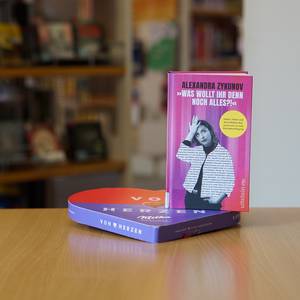Auf einer Schachtel Pralinen steht ein Buch mit dem Titel "'Was wollt ihr denn noch alles?!'"