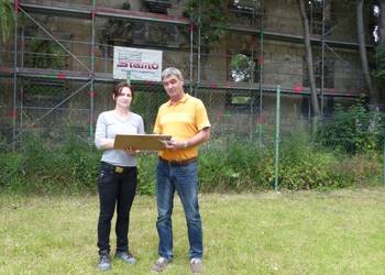 Cathrin Bothmann, Sculptor Werkstatt Für Restaurierung und Bildhauerei, und Jörg Wolansky, Gebäudemanagement Stadt Halberstadt stehen vor der barocken Sandsteinfassade und betrachten die ersten auf Papier aufgenommenen Ergebnisse der Untersuchung.