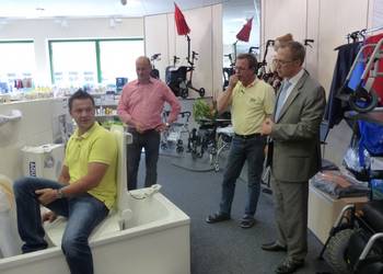 Orthopädietechniker Sebastian Diße führt den Gästen, Oberbürgermeister Andreas Henke (rechts) und Thomas Rimpler (links) einen Badewannenlift vor. Geschäftsführer Klaus Diße erläutert die Funktion des Hilfsgerätes.