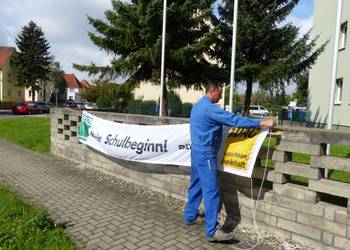 Steffen Dalljo, Mitarbeiter des Stadt- und Landschaftspflegebetriebes (Stala), montiert im Bereich Klusstraße/Eitzstaße ein Transparent zur Schulwegsicherung.