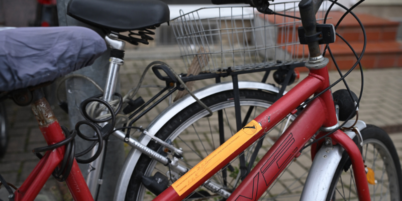 Frau Förster aus der Abteilung Ordnung und Sicherheit kennzeichnet ein verlassenes Fahrrad mit dem neuen Aufforderungsaufkleber © Holger Wegener PM Aufforderungsaufkleber für verlassene Fahrräder im Einsatz